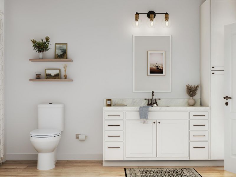 Modern bathroom with white cabinets, a toilet, wall shelves, and framed art above a marble sink.