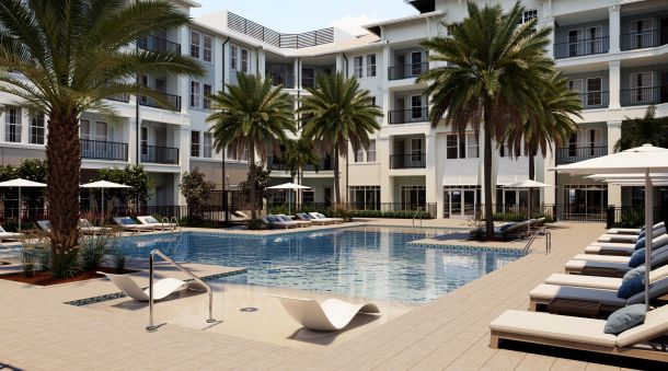 Modern apartment complex with palm trees, lounge chairs, and a swimming pool under a sunny sky.
